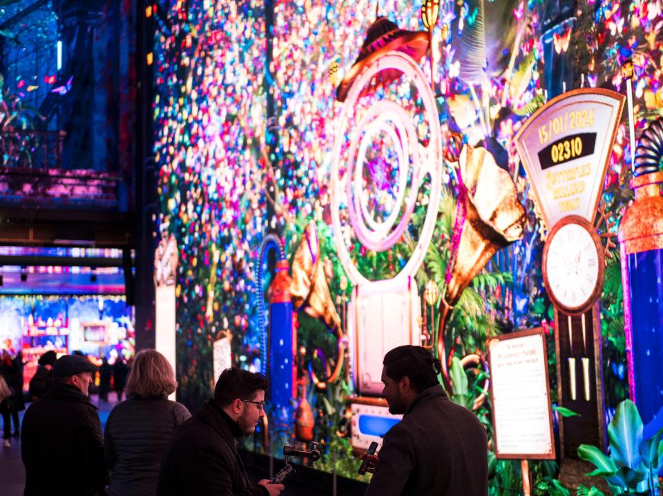 Tourists watching a large digital display at a London tourist attraction.