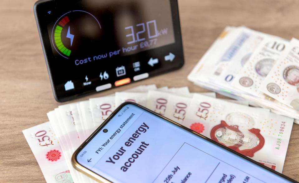 Smart meter display, phone energy bill, and British banknotes.