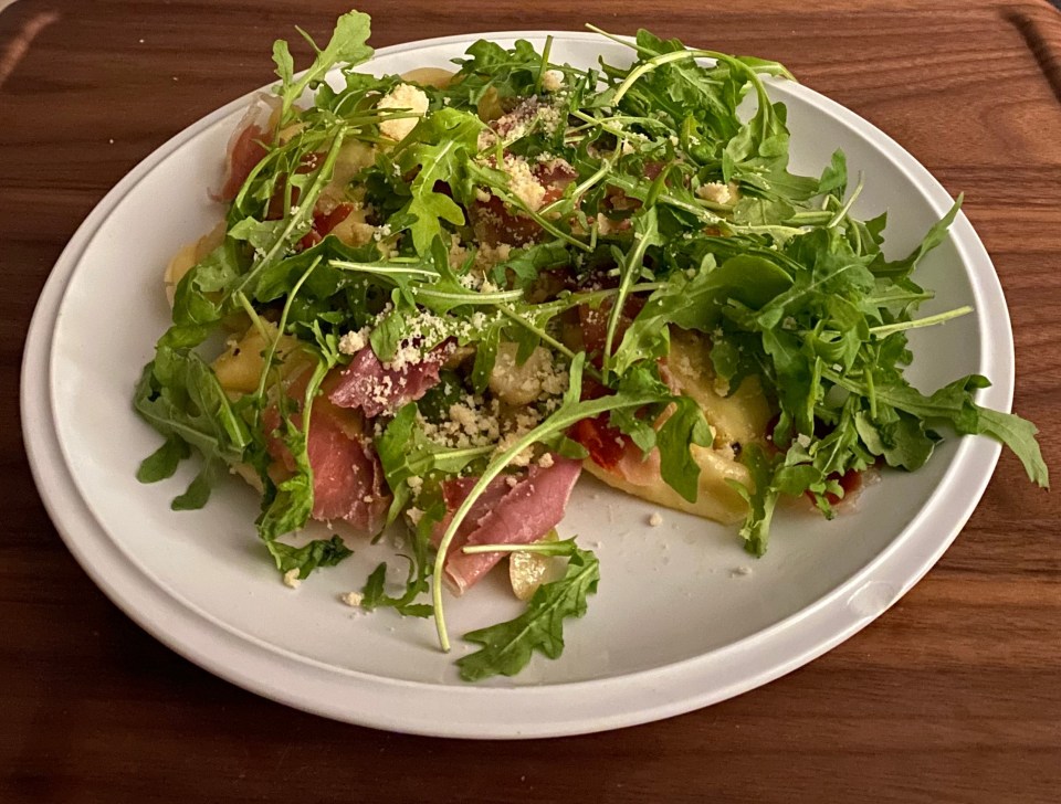 Plate of pasta with prosciutto and arugula.