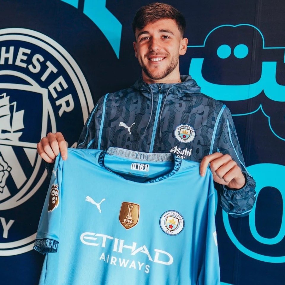 Man City player holding up a new team jersey.