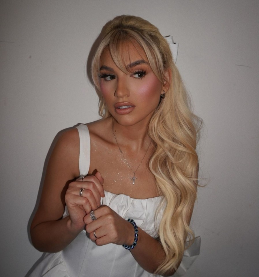 Portrait of Sacha Jones wearing a white top and jewelry.