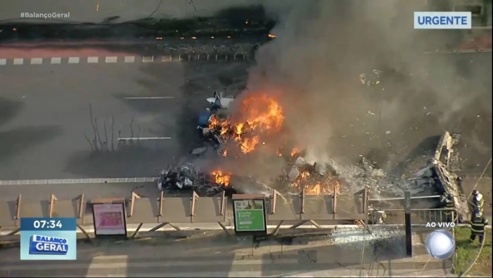 Burning wreckage of a plane crash on a roadway.