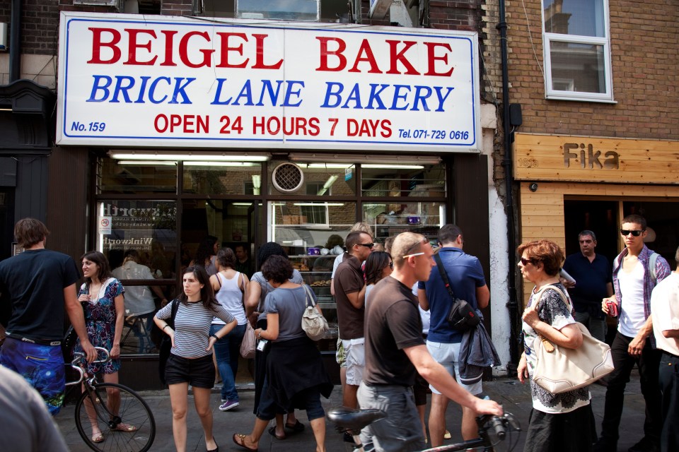 BD84MF People eating outside famous Bagel Bake bakery on Brick lane on Sunday Market day. This is the most famous bagel shop in London.