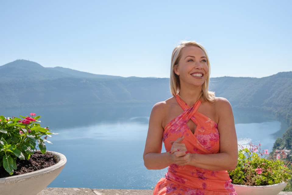 Woman in orange dress overlooking a lake and mountains.
