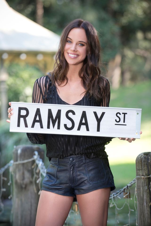Bonnie Anderson holding a Ramsay St sign.