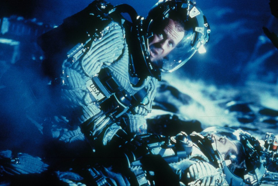 Still from *Armageddon* showing Bruce Willis' character tending to an injured astronaut.