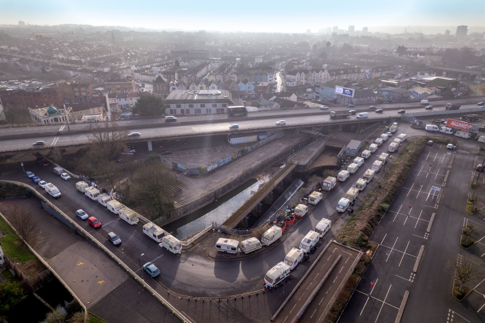 Aerial view of caravans parked near a waterway and a large parking lot.