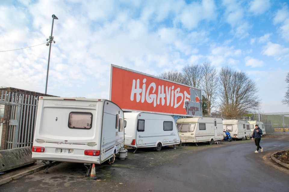 Several caravans parked near a billboard that says "HIGHVIBE".