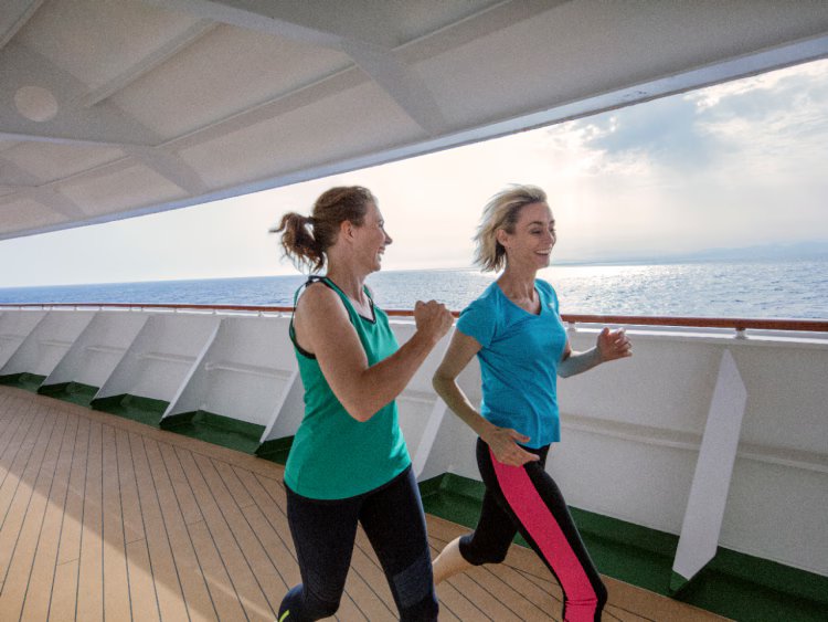 Two women jogging on a ship's deck.