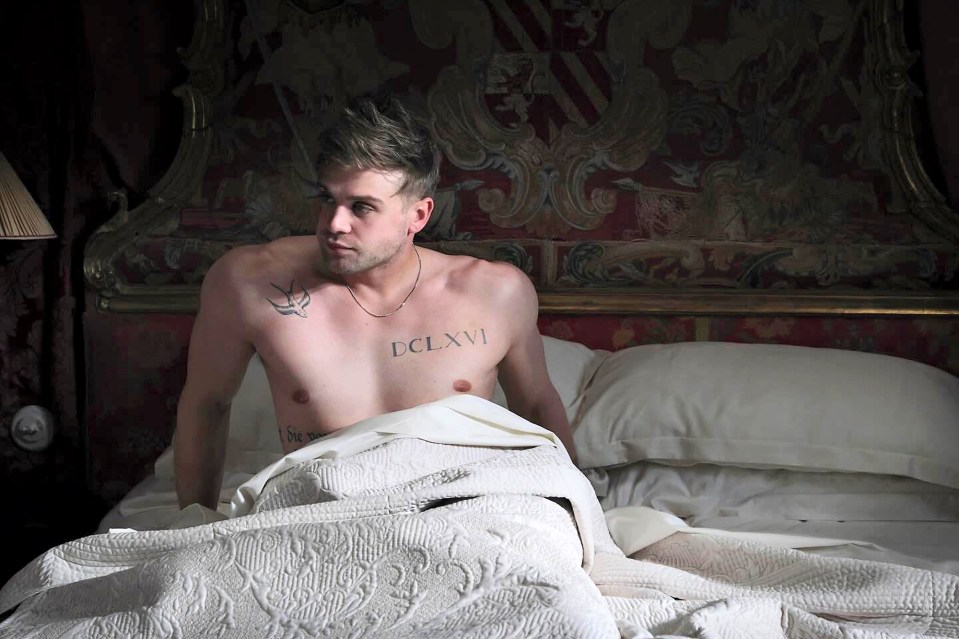 Man with tattoos sitting up in bed.