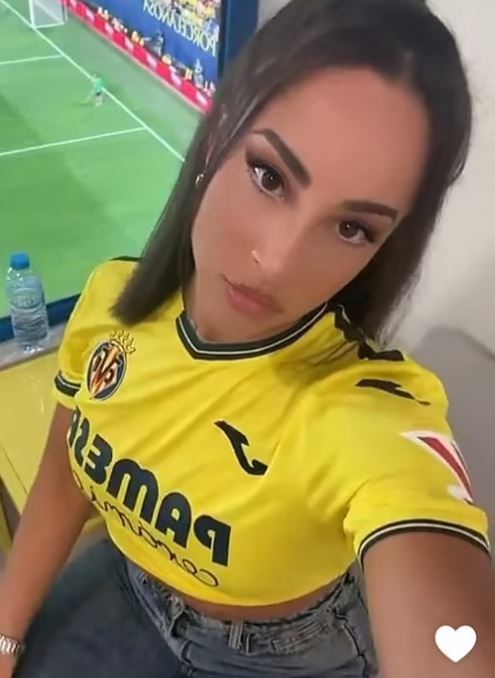 Woman in a yellow soccer jersey taking a selfie.