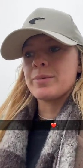 Woman wearing a beige baseball cap and a gray scarf.
