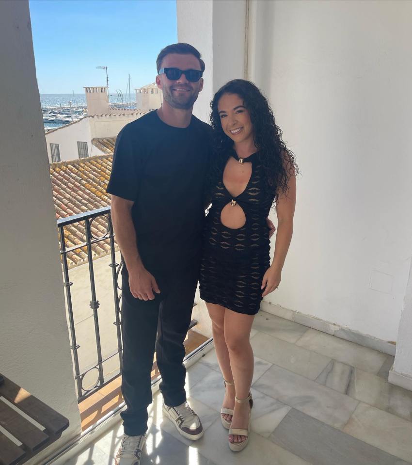 Couple posing on a balcony overlooking a harbor.