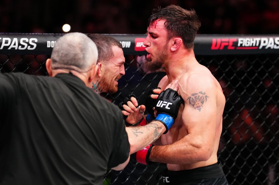 A UFC fighter is consoled by a referee after a fight.