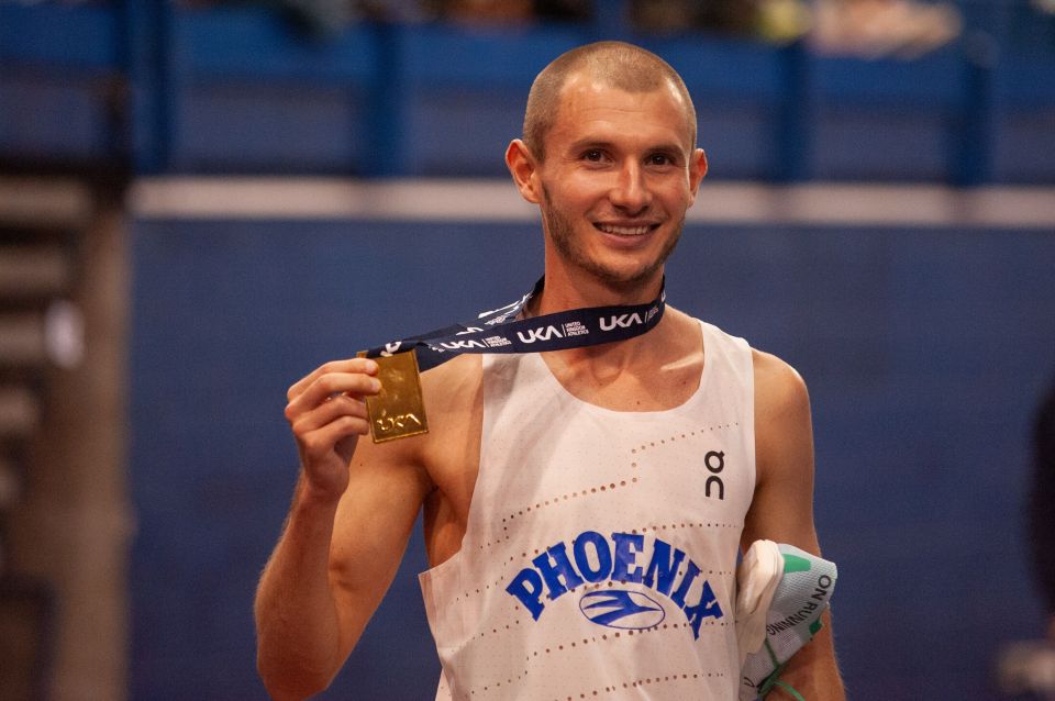 Athlete George Mills holding his gold medal after winning the 3000m final at the UK Indoor Championships.