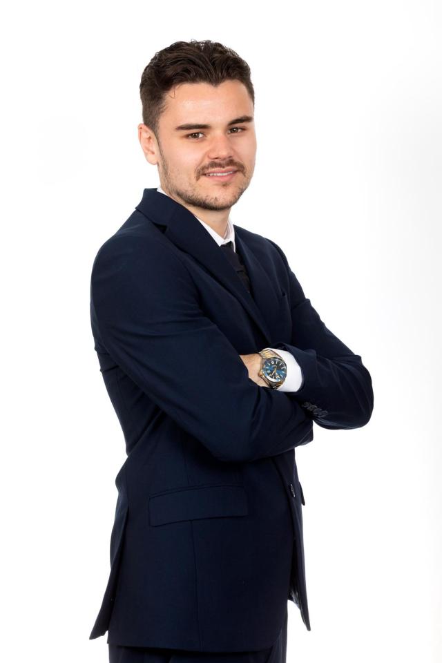 Portrait of a young man in a suit with his arms crossed.