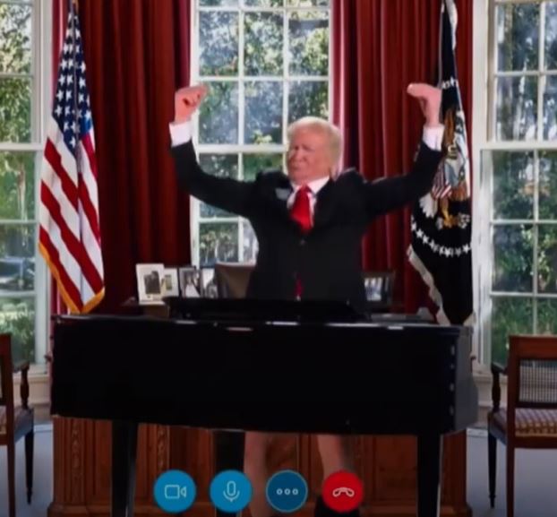 Donald Trump in a video call, arms raised, sitting behind a piano in the Oval Office.