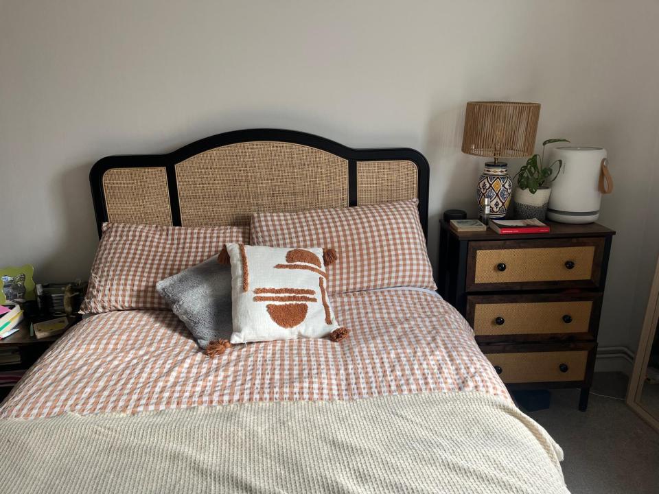 Bedroom with a bed featuring a rattan headboard and gingham bedding.