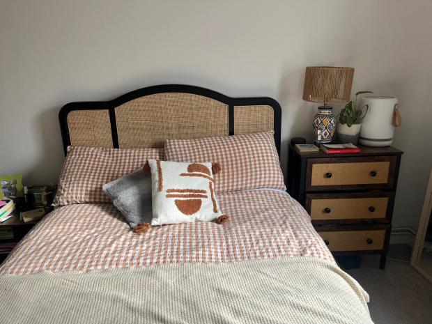 Bedroom with a bed featuring a rattan headboard and gingham bedding.