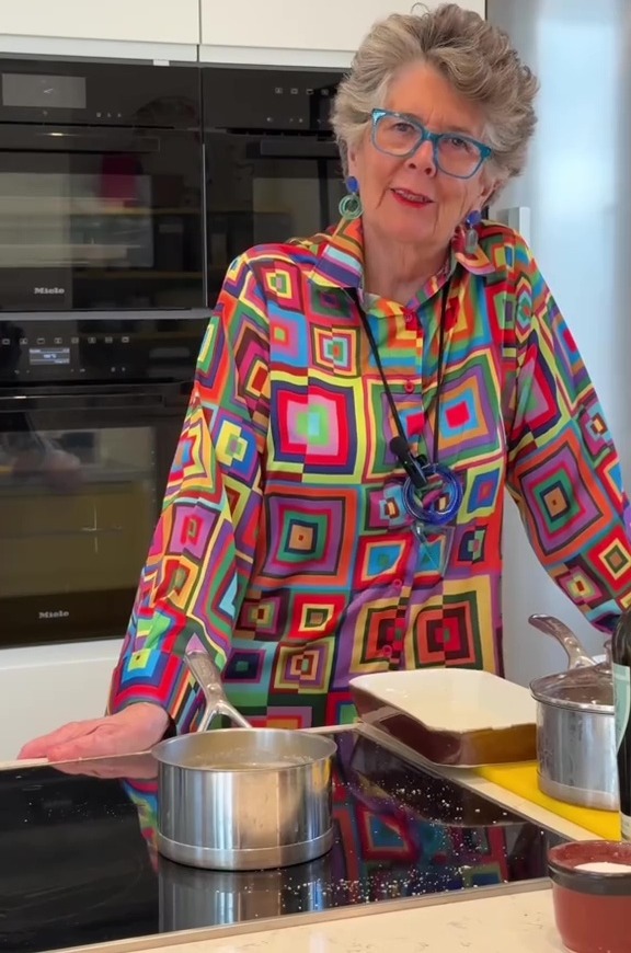 Prue Leith demonstrating a cooking technique in her kitchen.