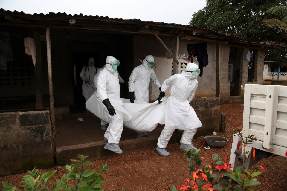 Nurses in protective gear carry the body of an Ebola victim.