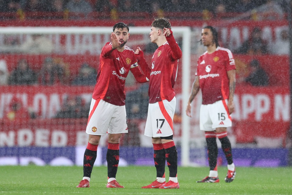 Alejandro Garnacho and Bruno Fernandes of Manchester United talking on the pitch during a rain-soaked game.