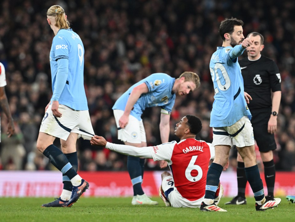 Arsenal's Gabriel pulling on Erling Haaland's shorts during a match.