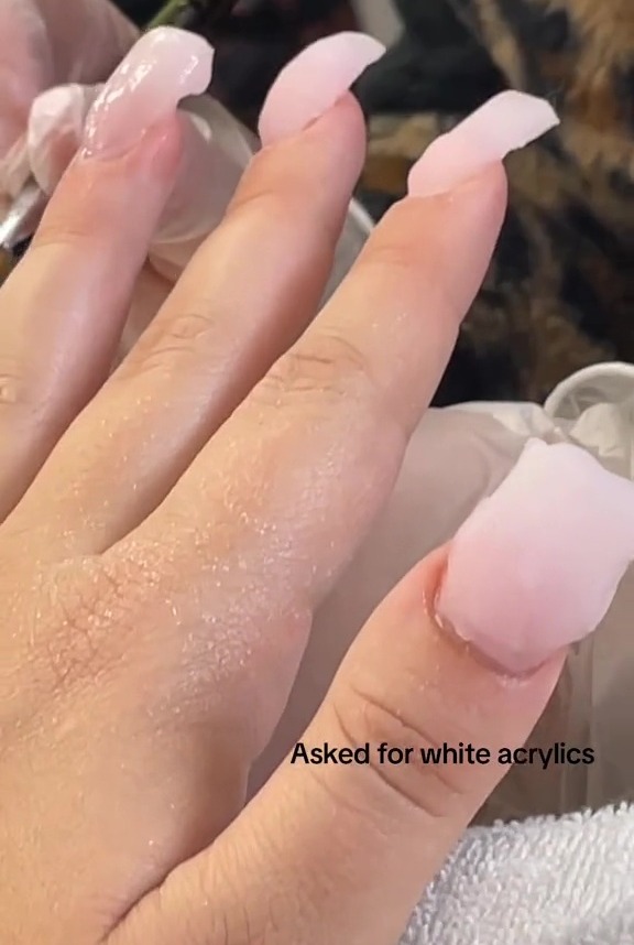 Pink acrylic nails being applied unevenly.