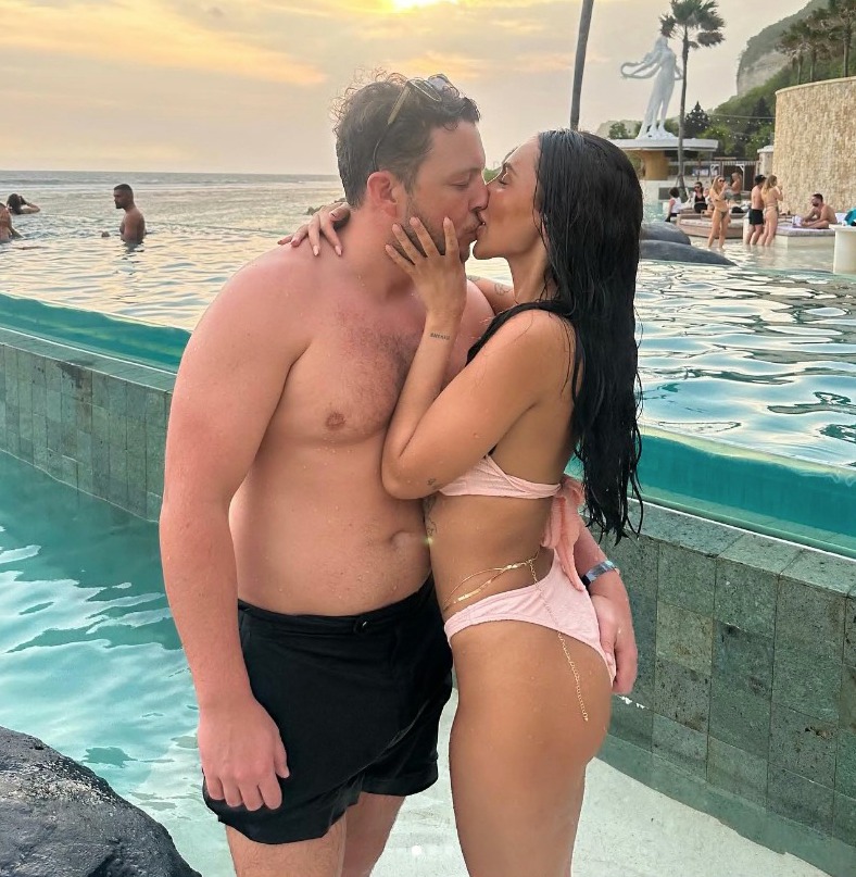 a man and woman kissing in front of a swimming pool