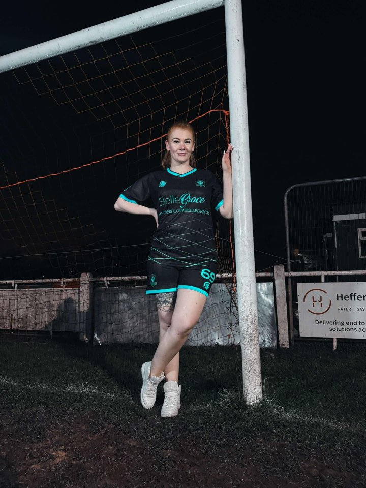 Woman in a soccer uniform leaning against a goalpost.
