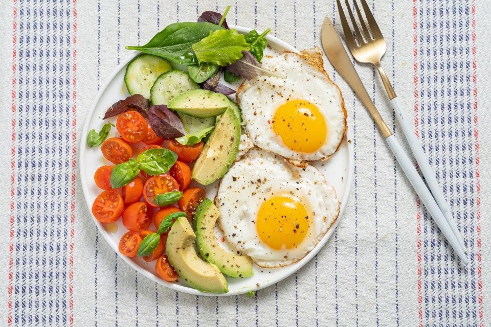 Fried eggs with avocado, tomato, and cucumber salad.