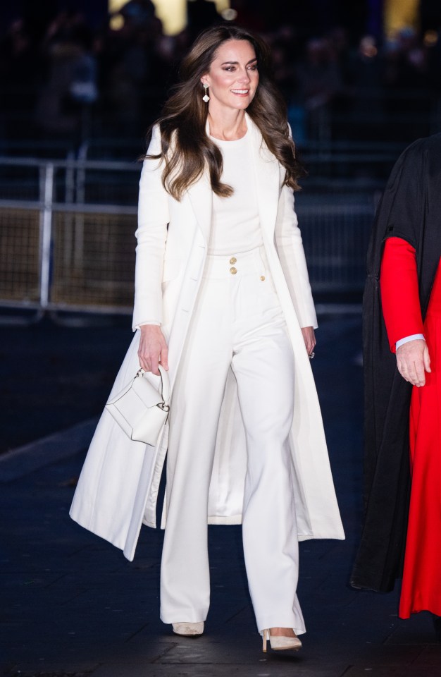Catherine, Princess of Wales, in a white coat and pantsuit, attends a Christmas carol service.