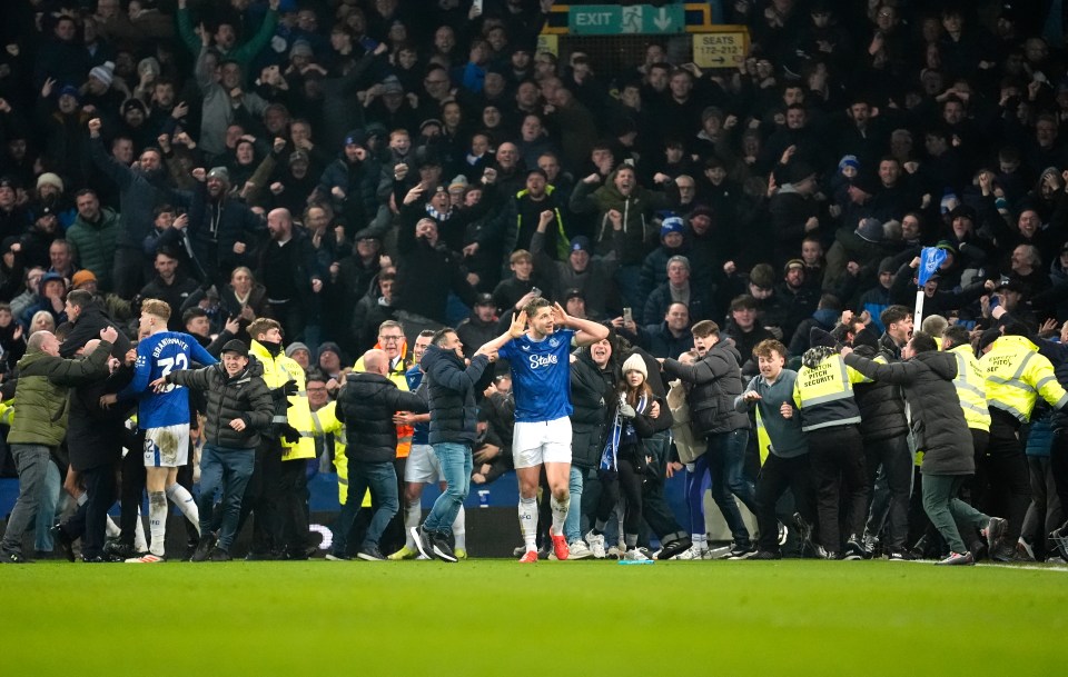 Everton's James Tarkowski celebrates a goal as fans rush the pitch.
