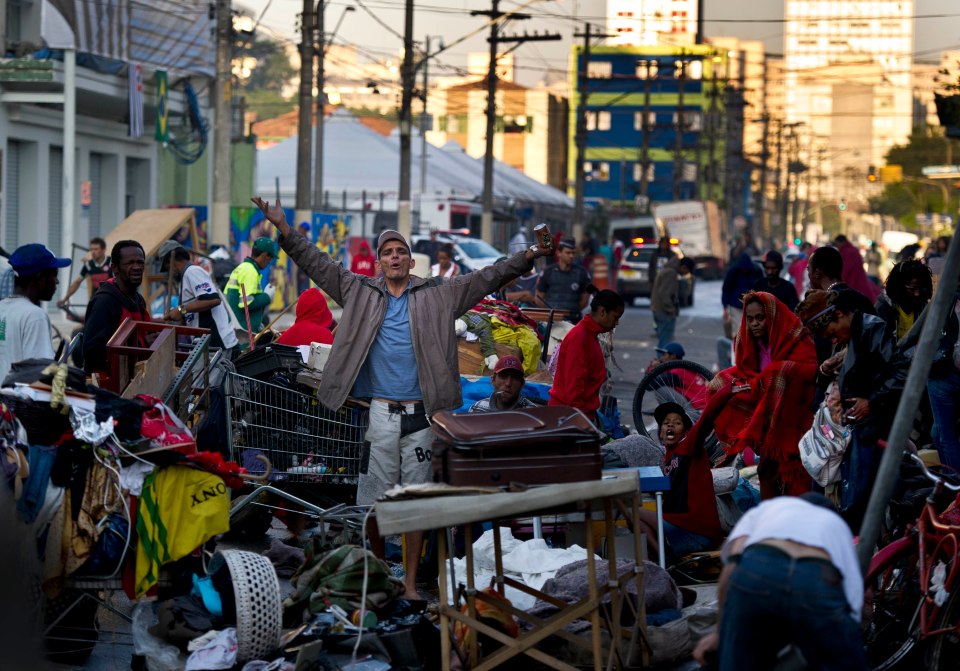 Street scene in Cracolandia, Sao Paulo, showing people amid belongings in a slum.