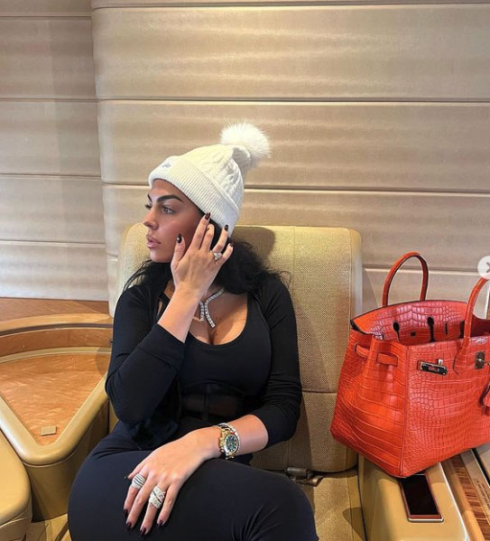 Woman on private jet wearing a white beanie and black outfit.