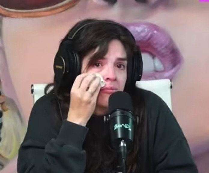 Dalma Maradona crying while wearing headphones and speaking into a microphone.