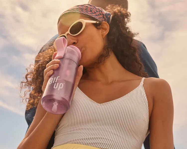 Woman drinking from a purple Air Up water bottle.