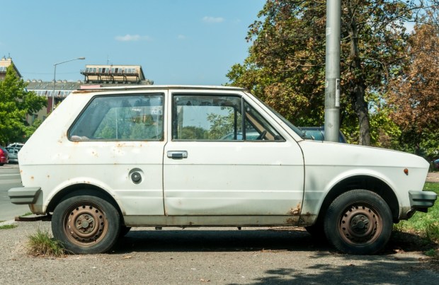 Novi Sad, Serbia. August - 29. 2018. Old white rusty Yugo car made in Zastava Kragujevac parked on the street in the city.