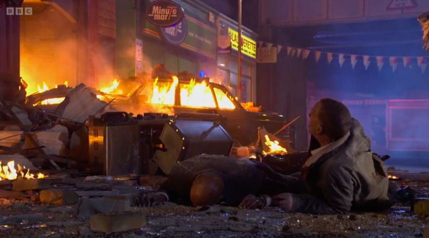 Aftermath of a pub explosion, with a burning car and injured people.