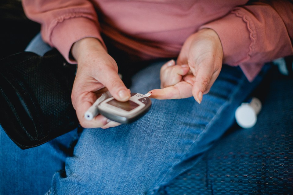 Close-up of a woman using a blood glucose meter.