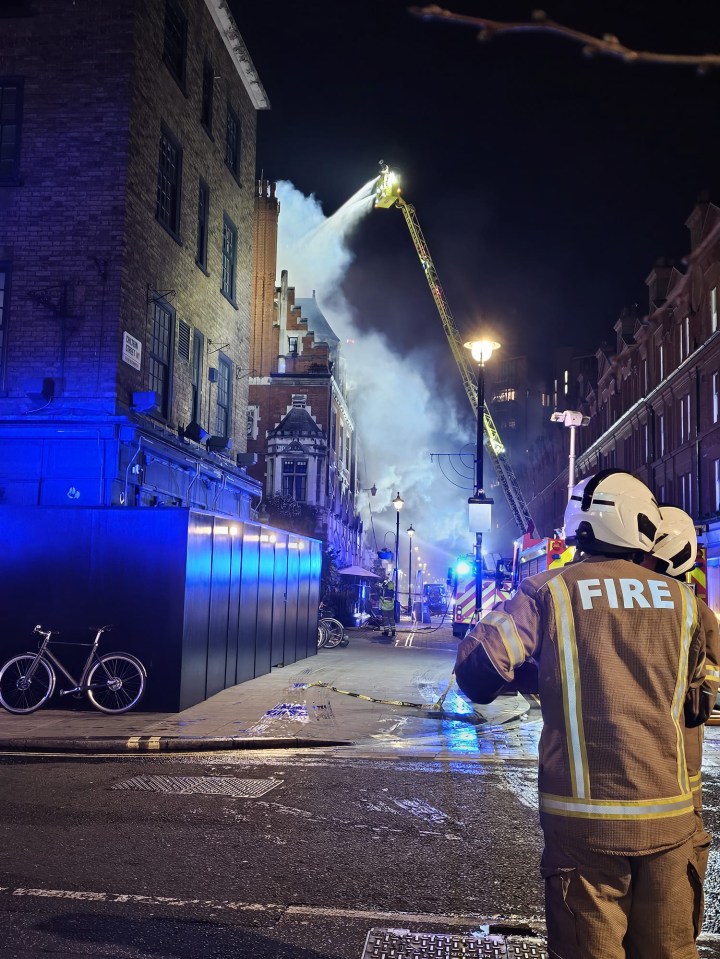 Firefighters battling a large fire at a building at night.