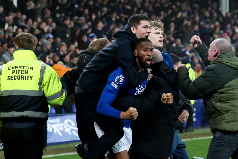 Everton player Beto is carried on the shoulders of teammates and a fan after scoring a goal.