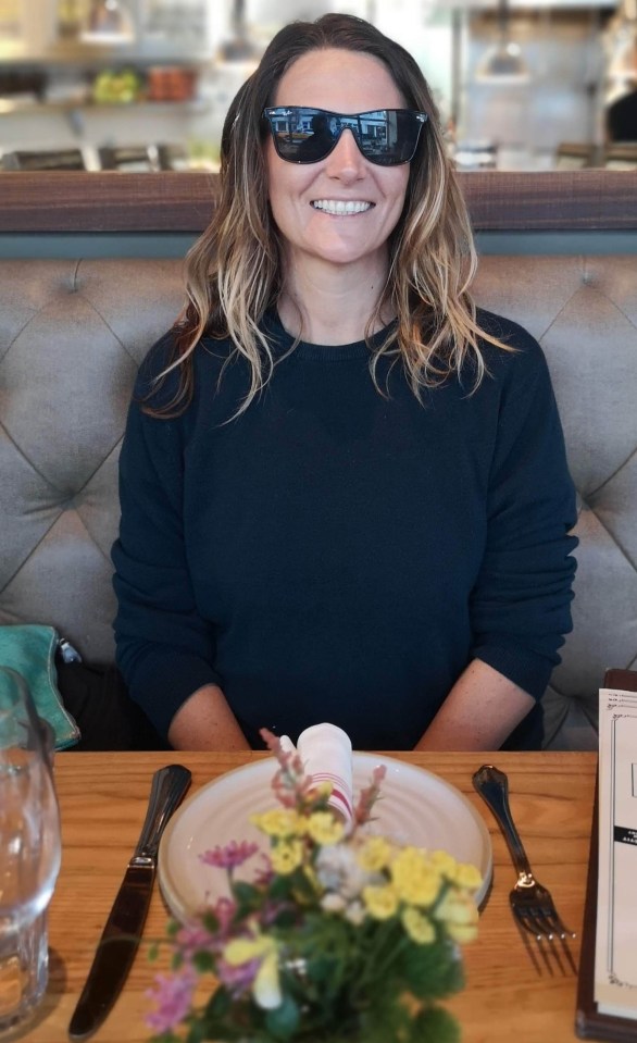 Woman wearing sunglasses sits at a restaurant table.