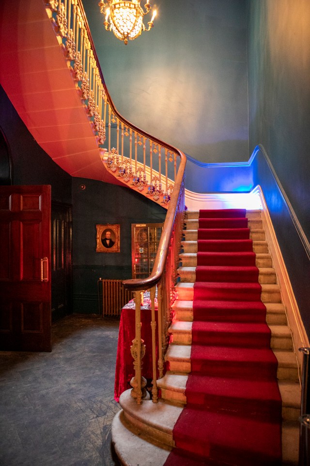 A red-carpeted staircase in a mansion.