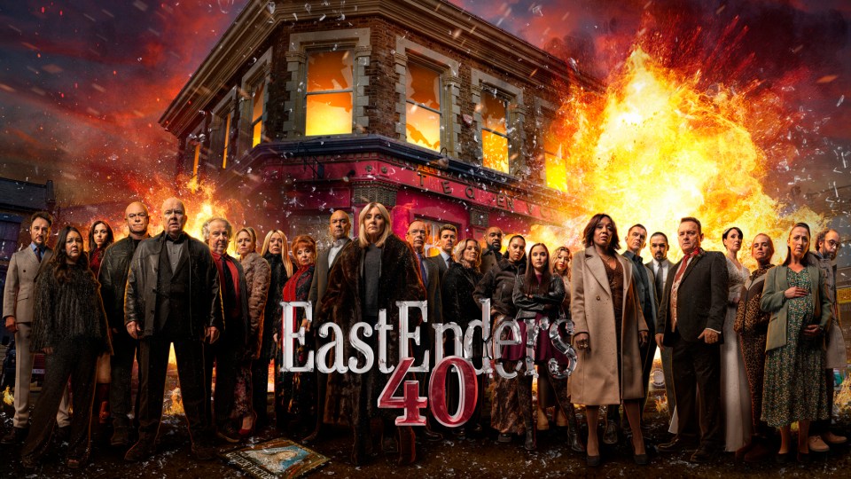 EastEnders 40th anniversary cast photo in front of a burning building.
