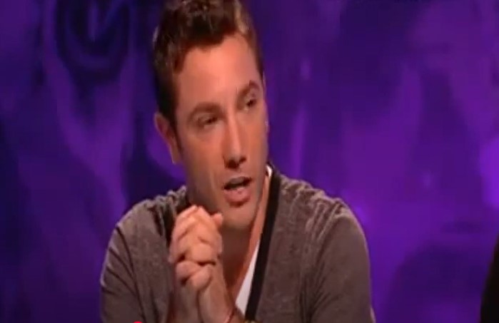 Gino D'Acampo speaking on a purple-lit television set.