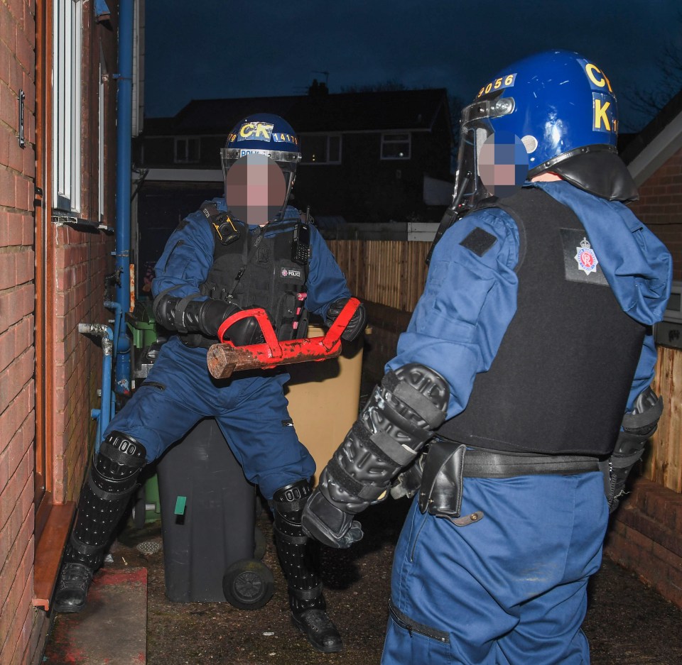 Police officers raiding a suspected drug house.