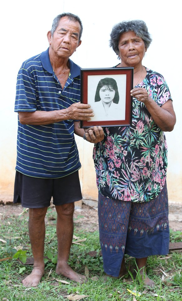 Elderly Thai couple holding a framed photo of their daughter.
