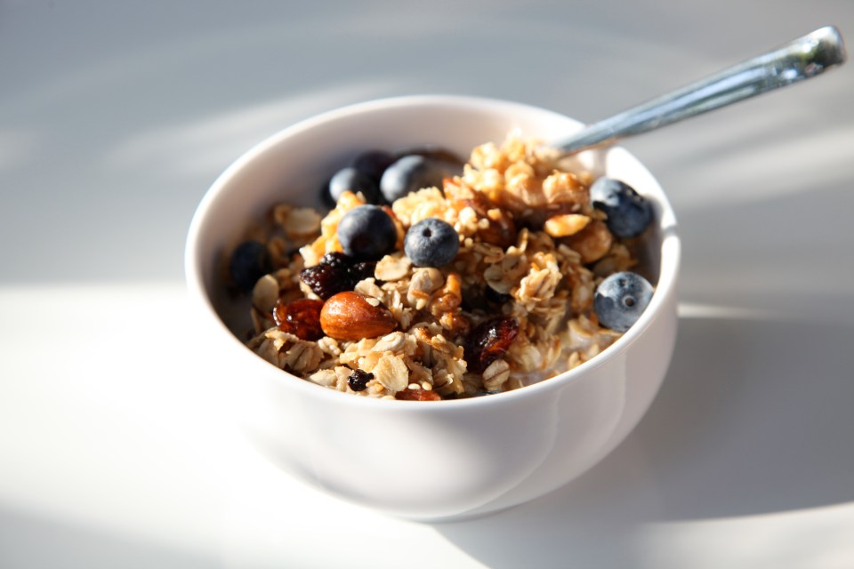 Homemade granola with almonds and blueberries in a white bowl.