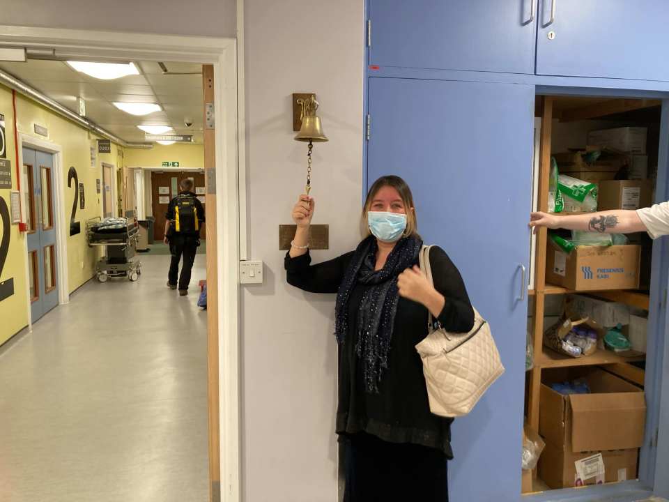 Woman ringing a hospital bell after successful brain tumour surgery.